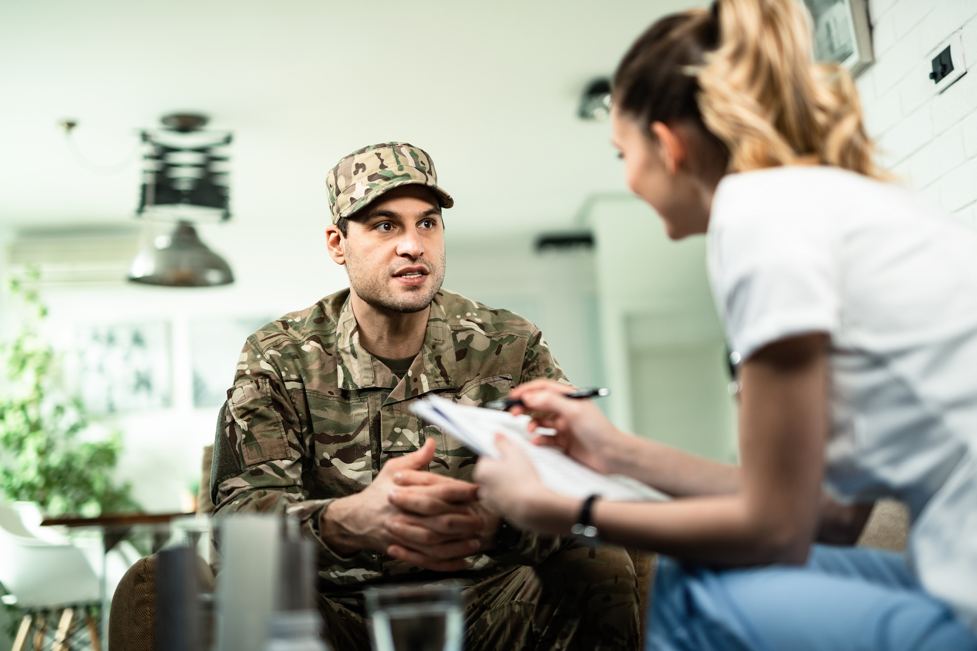 Image of a young military man talking to healthcare worker who is visiting him at home.